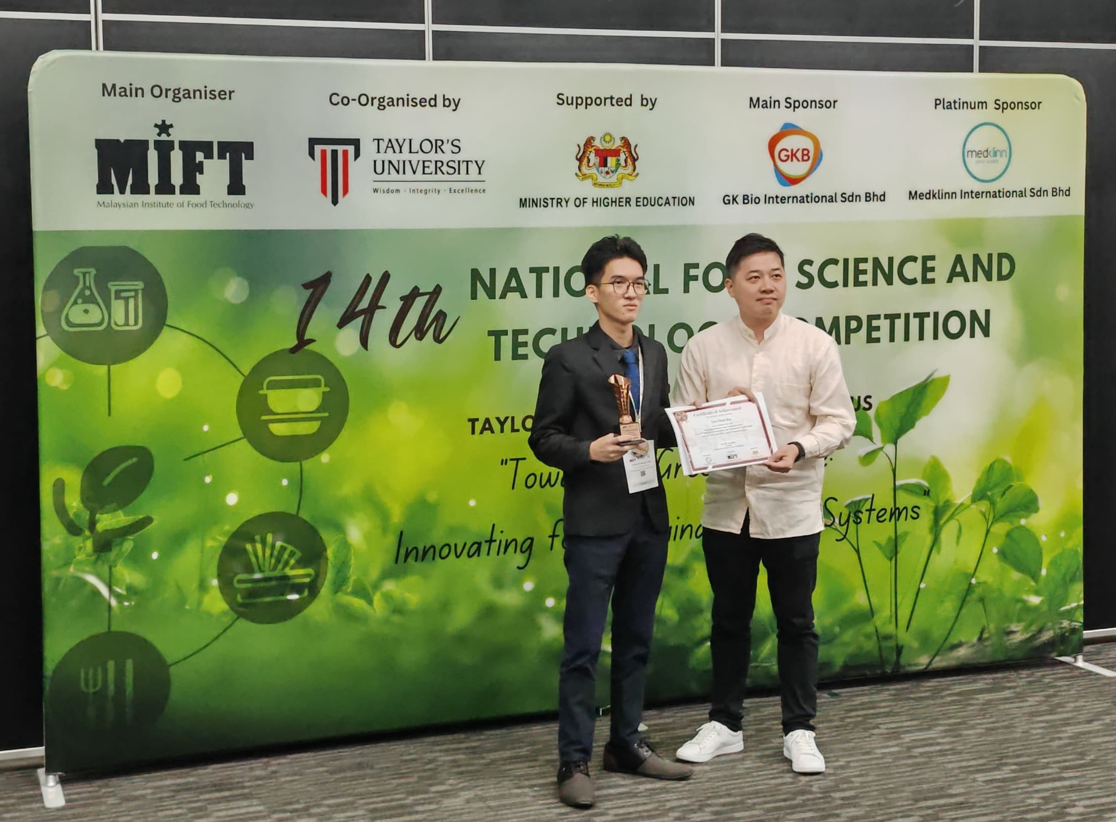 Loo receiving a trophy and certificate as the second runner-up in the Postgraduate Research Paper Competition (Oral)