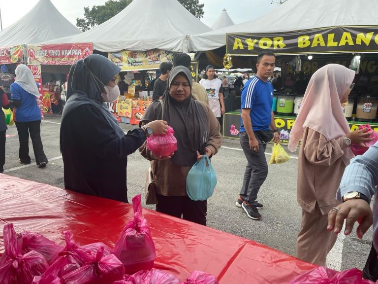 
Team members handing out bubur lambuk to the community