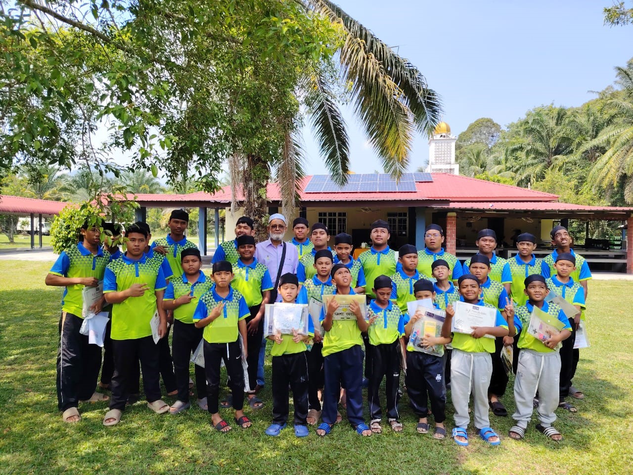 Chairperson of Pertubuhan Kebajikan Anak-anak Yatim/Miskin Dahikmah, Tuan Haji Jamal (in purple), with the residents holding their prizes from the <i>Shine Bright with Solar Energy</i> colouring contest