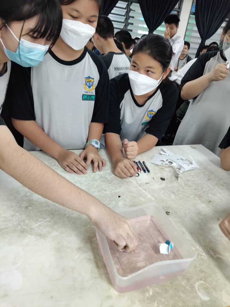 Students watching paper flowers bloom as they learn about capillary action