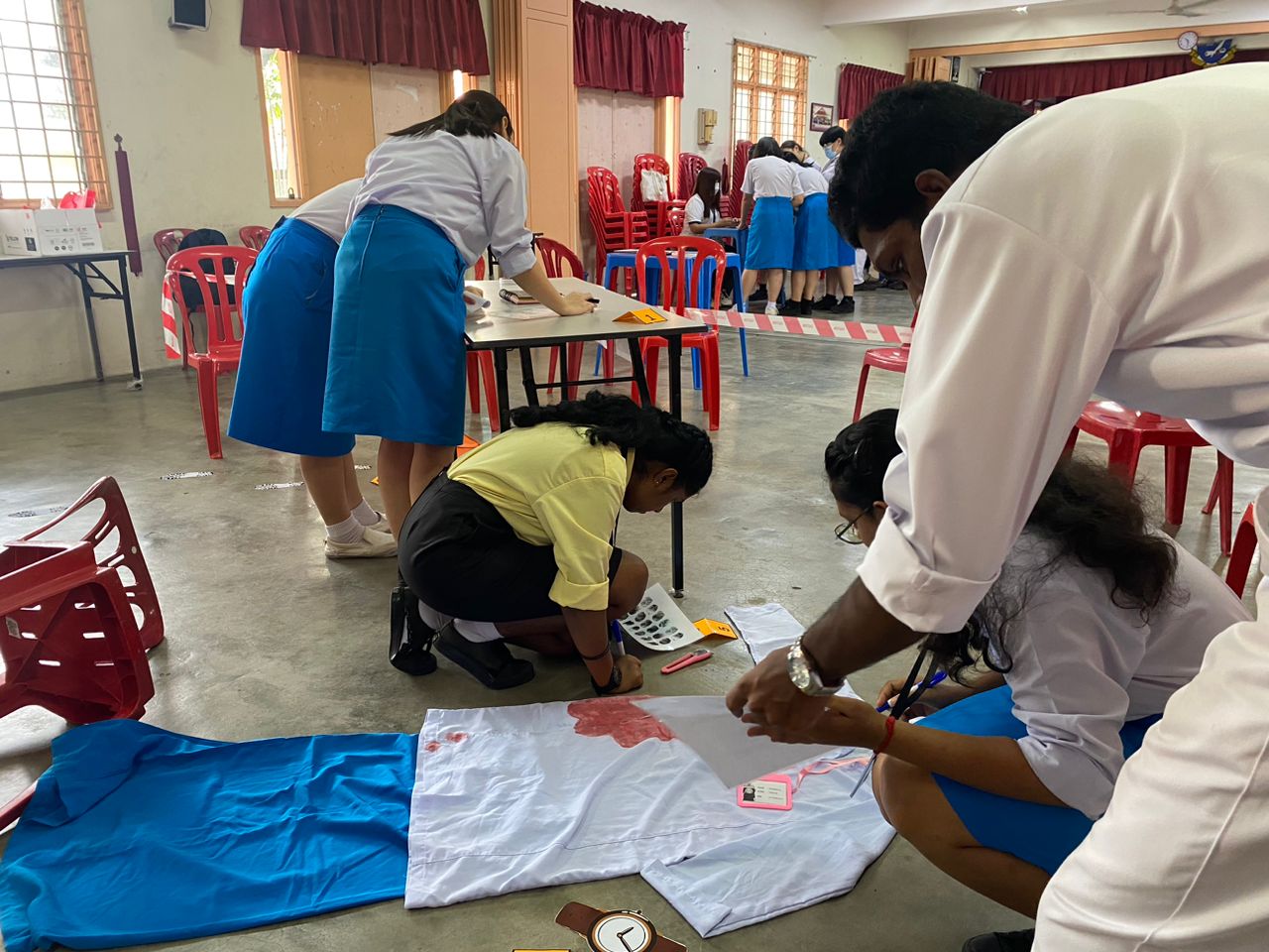 Participants at Murder Mystery Station examining clues and evidence to solve the case, putting their critical thinking and teamwork skills to test