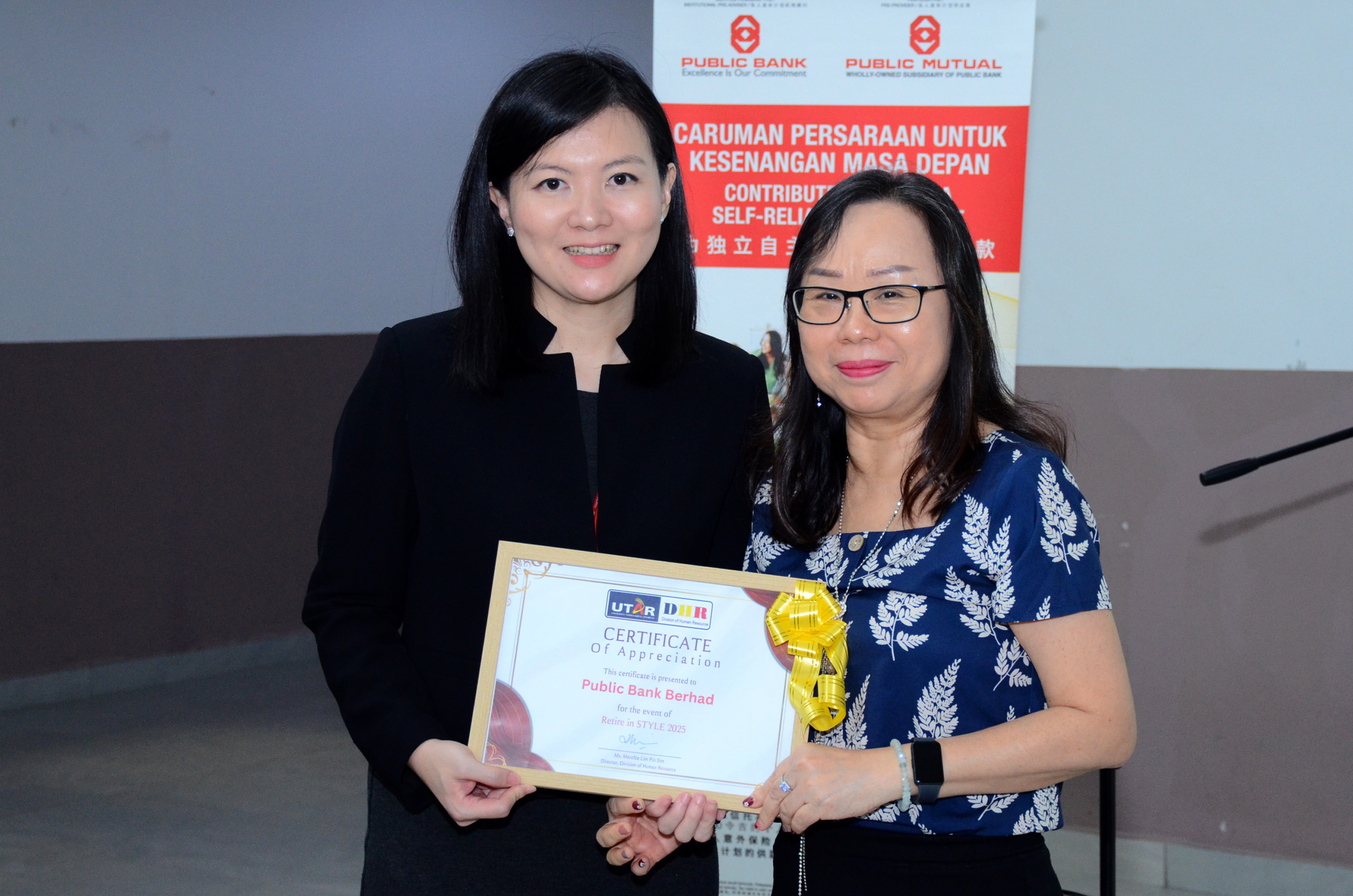 Ms Marchie Lim (right) presented a Certificate of Appreciation to the representative of Public Bank, Ms Catherine Ng (left)