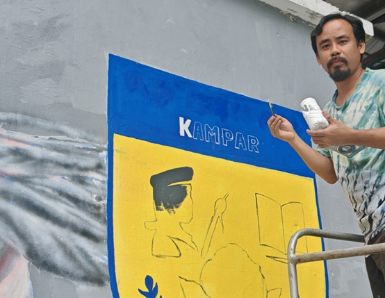 Mr Abdullah painting the school emblem of SMK Methodist ACS Kampar as part of the collaborative mural project