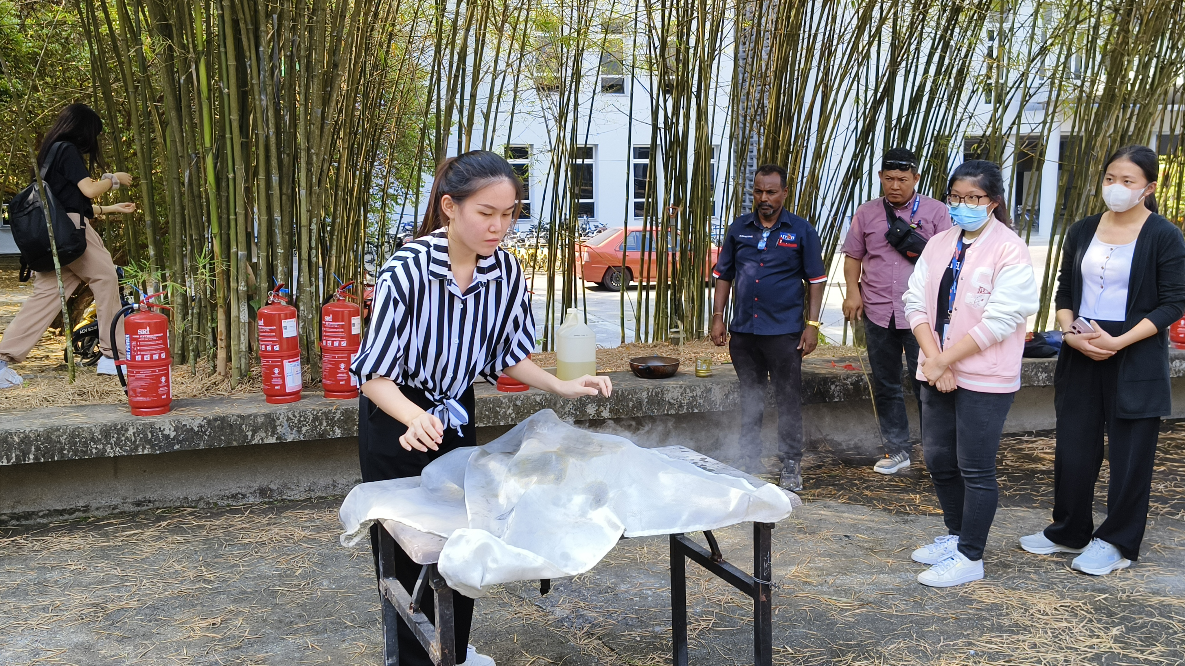 Students putting out fires on a stove using a fire blanket