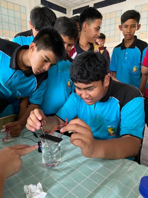 Students observing hydrogen gas production through electrolysis