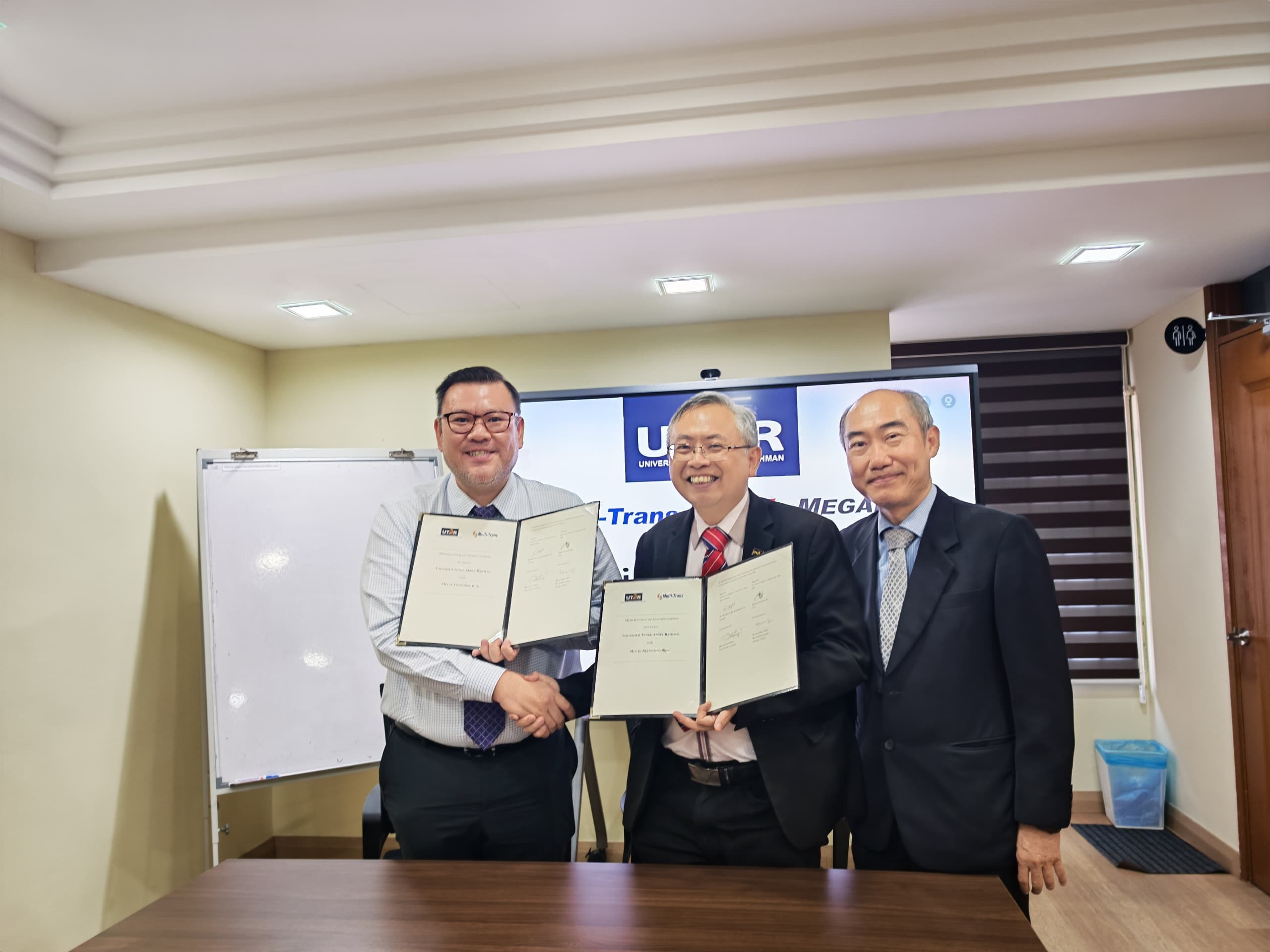 From left: Mr Edwin Tan and Prof Dato’ Ewe exchanging the signed MoU, witnessed by Dr Lim 