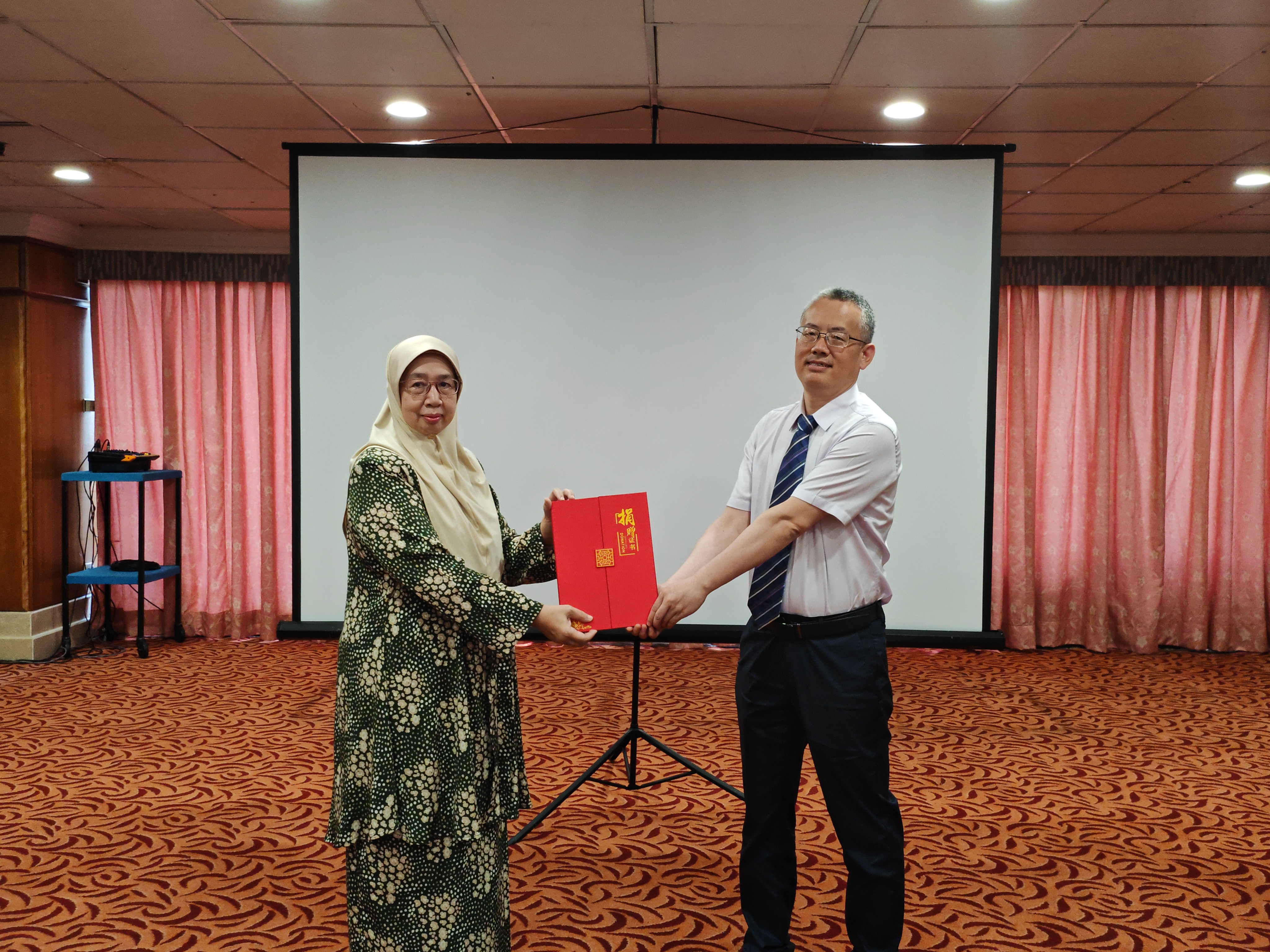 Prof Zuraidah (left) receiving certificate and the list of donated books from Mr Weng
